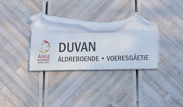 Närbild skylt på Duvans äldreboende som i överkanten har en liten kappa av snö.